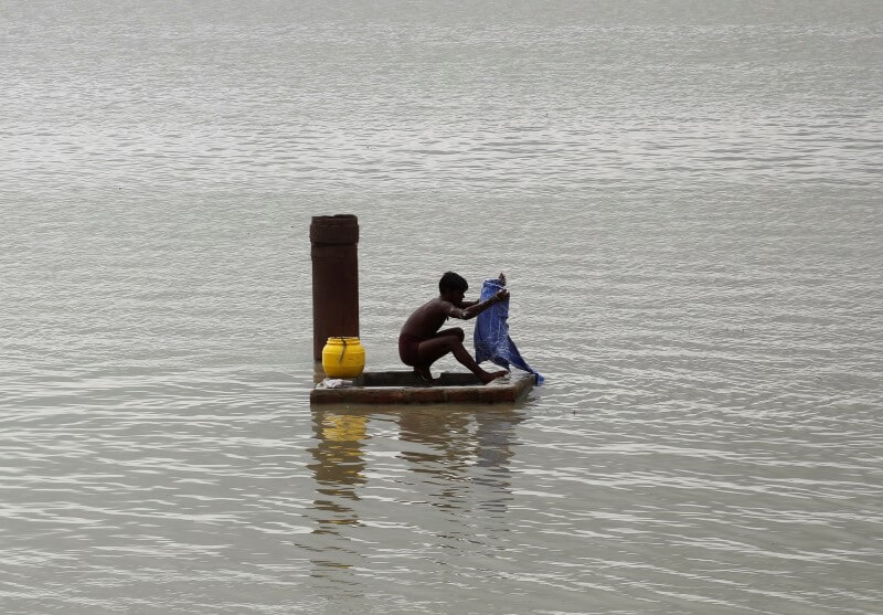 A man washes clothes on the flooded banks of river Ganga after heavy rains in Allahabad, India, July 14, 2016. REUTERS/Jitendra Prakash