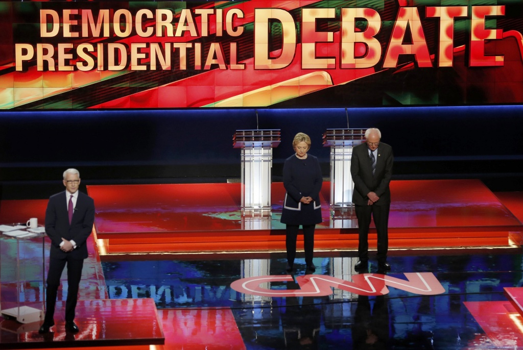 Democratic U.S. presidential candidates Hillary Clinton and U.S. Senator Bernie Sanders observe a moment of silence for the late U.S. first lady Nancy Reagan as moderator Anderson Cooper looks on before the start of the Democratic U.S. presidential candidates' debate in Flint, Michigan, March 6, 2016. REUTERS/Jim Young