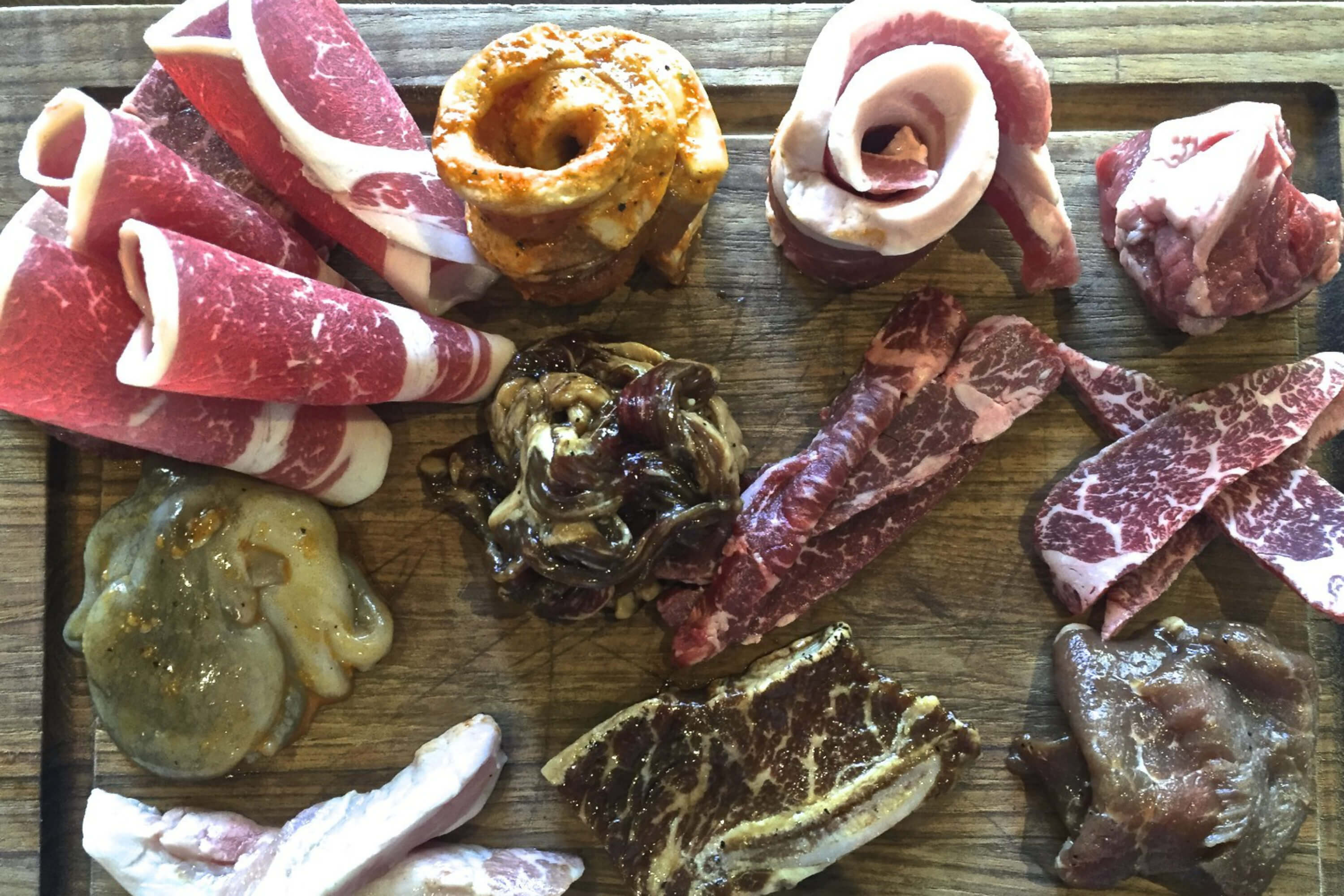 Korean barbecue offerings at Hanjip. Top row: brisket, marinated pork belly, pork belly, lamb. Middle row: baby octopus, beef bulgogi, skirt steak, short rib. Bottom row: pork jowl, marinated short rib, marinated pork shoulder. Credit: Copyright 2016 David Latt