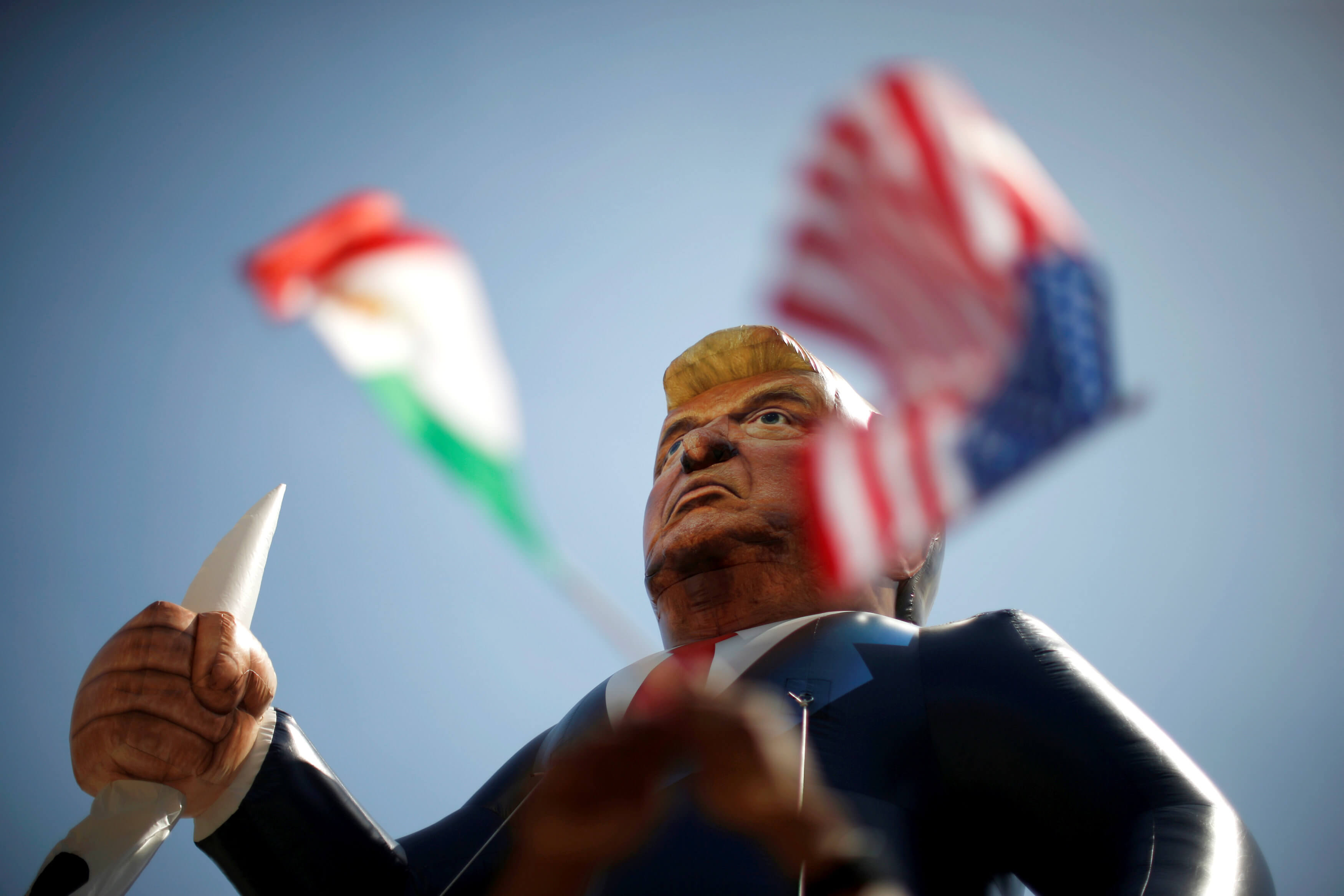 Mexican and U.S. flags are seen under an inflatable effigy of Republican presidential candidate Donald Trump during a march at an immigrant rights May Day rally in Los Angeles, California, U.S., May 1, 2016. REUTERS/Lucy Nicholson